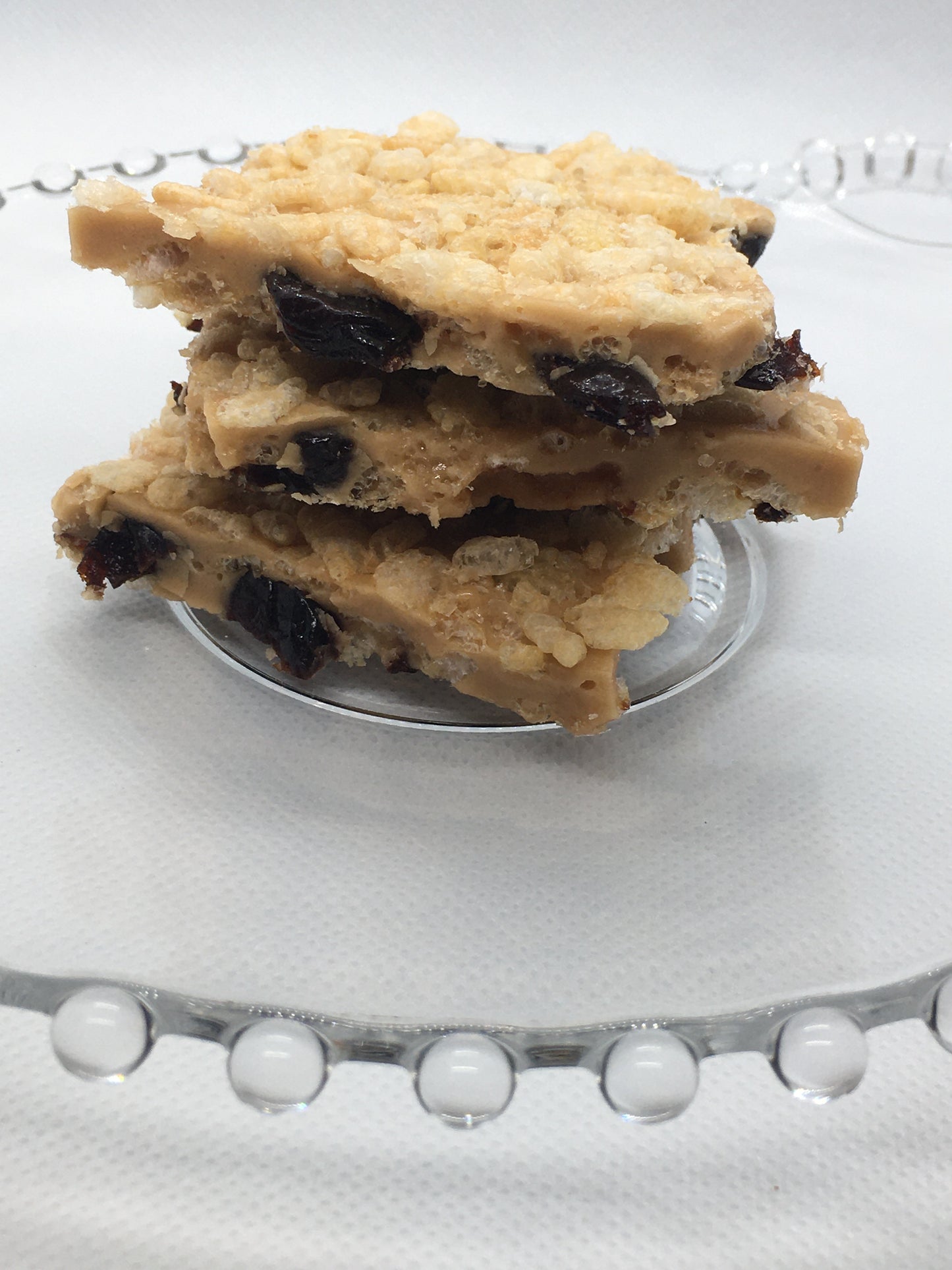 Toffee with rice crispies and dried cherries in it on a decorative glass plate.